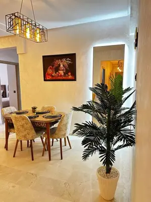 a dining room with a table and a palm tree at App centre-ville in Marrakech
