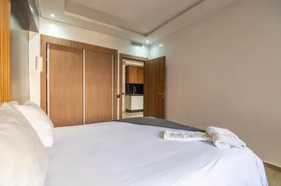 a bedroom with a white bed with a wooden headboard at Royal KING Bed SUITE W/POOL in Marrakech