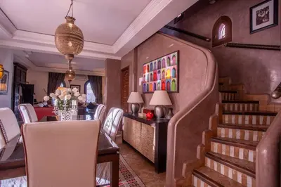 a dining room with a table and chairs and a staircase at Dar Ines - Palmeraie, 250m2, pool, patio, terrace in Marrakech