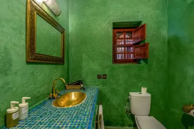 a green bathroom with a sink and a toilet at Riad Amalia in Marrakech