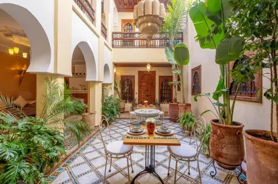 a courtyard with a table and chairs and plants at Riad Amalia in Marrakech