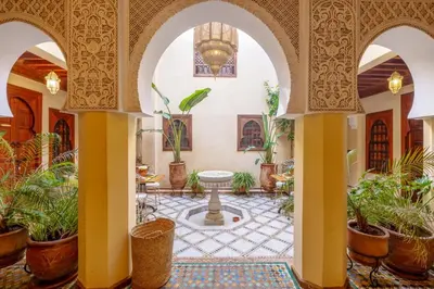 a courtyard with a fountain and potted plants at Riad Amalia in Marrakech