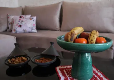 a green bowl of fruit on a table with a couch at appartement confort calme propre WIFI in Marrakech