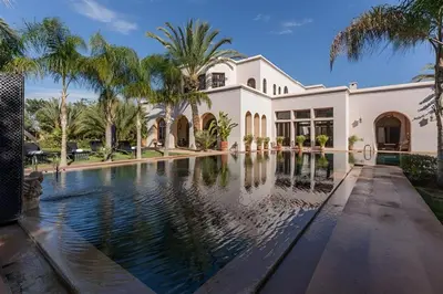 a house with a swimming pool and palm trees at Palais FARAH in Marrakech