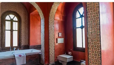 a bathroom with a tub and a toilet and two windows at Palais FARAH in Marrakech