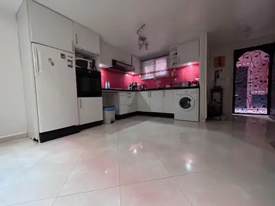 a large kitchen with white appliances and pink walls at Riad le pélican in Marrakech