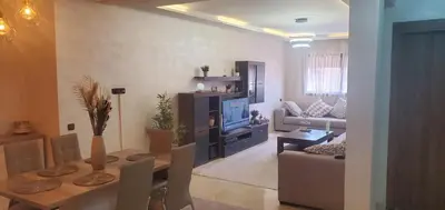 a living room with a couch and a table with a television at Super appartement haut standing ensoleillé gare in Marrakech