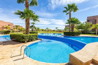 a swimming pool with palm trees in a resort at Golf Prestigia, grande piscine, jardins in Marrakech