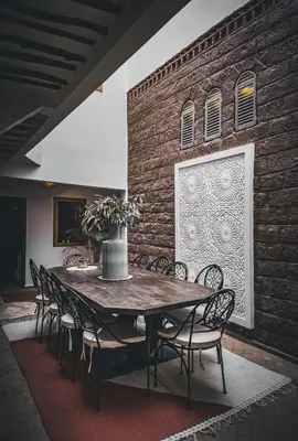 a dining room table with chairs and a brick wall at Riad & SPA Privé - La Perle d'Orane - Marrakech in Marrakech