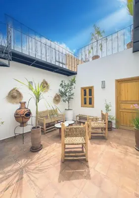 a living room with benches and potted plants at Riad & SPA Privé - La Perle d'Orane - Marrakech in Marrakech