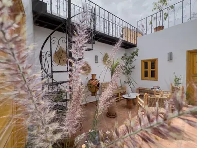a courtyard with a staircase and flowers in a house at Riad & SPA Privé - La Perle d'Orane - Marrakech in Marrakech