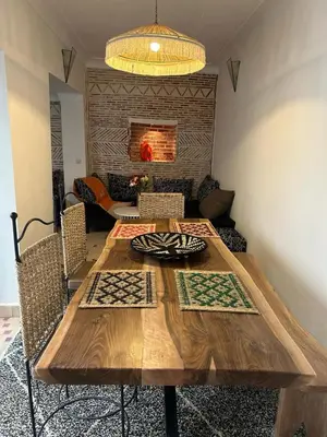 a dining room with a wooden table with chairs at Riad Les Jardins de Kenza, idéalement situé, 5 minutes de la place Jemaa El Fna in Marrakech