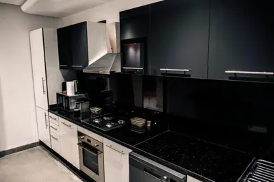 a kitchen with black counters and white cabinets at Appartement Luxe Riad Garden Marrakech 3 piscines in Marrakech