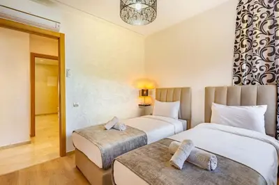 a hotel room with two beds and a chandelier at Prestigia Saphir,Piscine, Jardin in Marrakech
