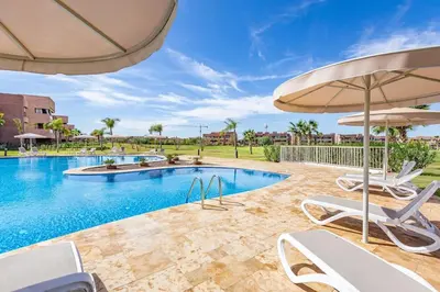 a swimming pool with chairs and an umbrella at Prestigia Saphir,Piscine, Jardin in Marrakech
