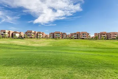 a golf course with apartment buildings in the background at Prestigia Saphir,Piscine, Jardin in Marrakech