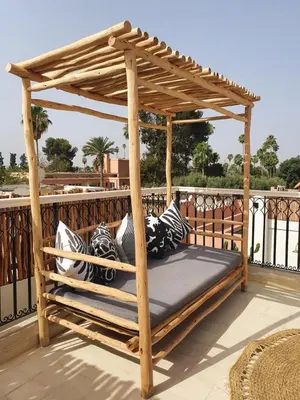 a wooden gazebo with pillows on a balcony at Riad Fisaline en exclusivité pour vous à Marrakech in Marrakech