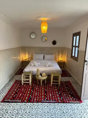 a bedroom with a bed with two chairs and a table at Riad Tarba & Spa in Marrakech