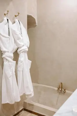 a bathroom with white towels hanging on a wall at Riad Le Sable Vert in Marrakech