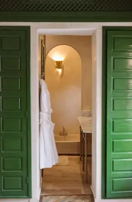 a bathroom with a tub and a green door at Riad Le Sable Vert in Marrakech