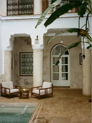 a patio with two chairs and a table and a door at Riad Le Sable Vert in Marrakech