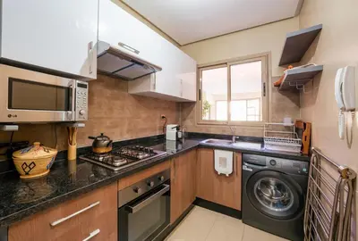 a kitchen with a washing machine and a microwave at Apart Confort Front Pool-Garden in Marrakech