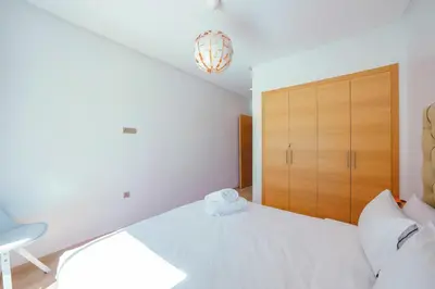 a white bedroom with a bed and a wooden cabinet at Apart Confort Front Pool-Garden in Marrakech