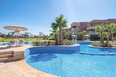 a swimming pool in a resort with palm trees at Apart Confort Front Pool-Garden in Marrakech