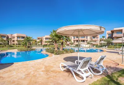 a swimming pool with two chairs and an umbrella at Apart Confort Front Pool-Garden in Marrakech