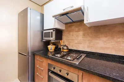 a kitchen with a stove and a refrigerator at Apart Confort Front Pool-Garden in Marrakech