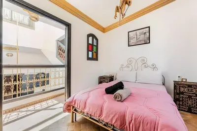 a bedroom with a pink bed and a large window at 16 Riads in Marrakech
