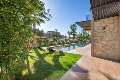 a couple of benches sitting on the grass next to a pool at Palais Rafi in Marrakech