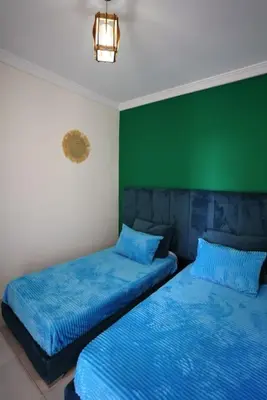 two beds in a room with a green wall at Comfy family flat 10 mins from Medina in Marrakech