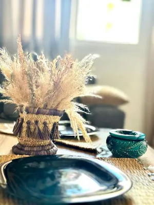 a table with a blue plate and a vase with feathers at Comfy family flat 10 mins from Medina in Marrakech