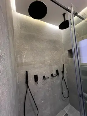 a bathroom with a shower with black fixtures on the wall at Luxe appartement à louer pour les familles in Marrakech