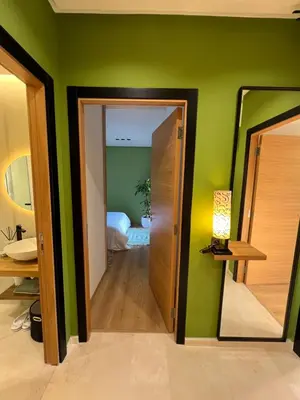 a room with green walls and a hallway with a mirror at Luxe appartement à louer pour les familles in Marrakech