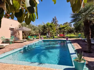 a swimming pool in a yard with palm trees at Manzal Lahbab, 2Villas 2Bungalows 2Piscines et Jardins in Marrakech