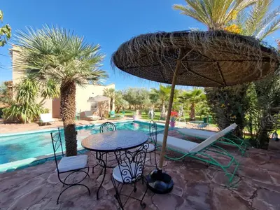 a table and chairs with an umbrella next to a pool at Manzal Lahbab, 2Villas 2Bungalows 2Piscines et Jardins in Marrakech