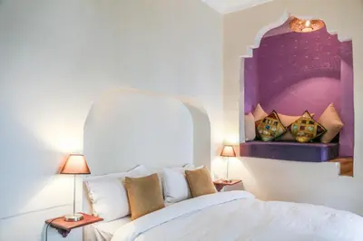 a bedroom with a white bed with a painting on the wall at Riad 11 Zitoune in Marrakech