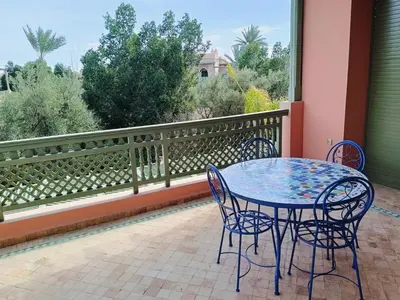a patio with a table and chairs on a balcony at Appartement HIBISCUS 3 chambres avec piscine in Marrakech