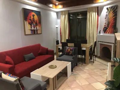 a living room with a red couch and a fireplace at Appartement HIBISCUS 3 chambres avec piscine in Marrakech