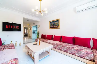 a living room with a red couch and a table at Central appartement in the heart of Guéliz in Marrakech
