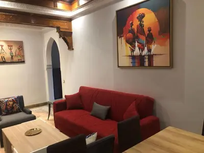 a living room with a red couch and a table at Appartements de charme à la palmeraie in Marrakech
