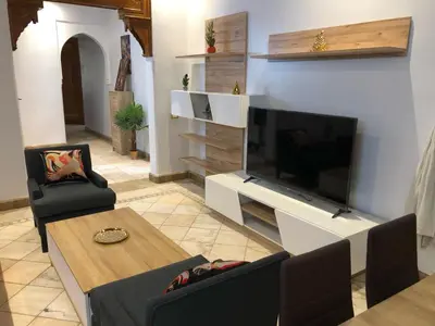 a living room with a large television and a table at Appartements de charme à la palmeraie in Marrakech
