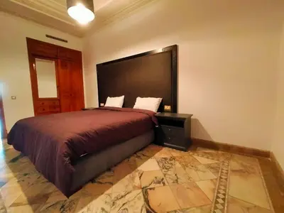 a bedroom with a large bed with a large headboard at Appartements de charme à la palmeraie in Marrakech