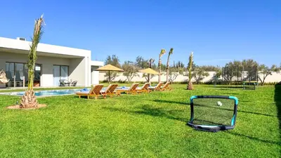 a golf cart sitting in the grass next to a pool at Villa KOEUR, piscine chauffée sans vis-à-vis à Marrakech in Marrakech
