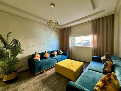 a living room with a blue couch and a table at Bel Appart Familial Majorelle in Marrakech