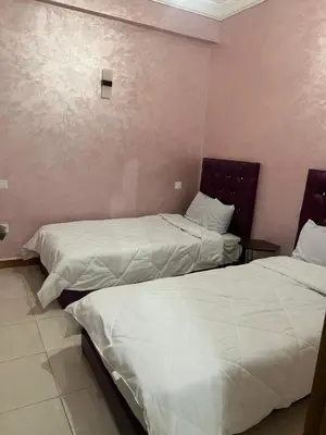 two beds in a hotel room with white sheets at Confort Abordable Louez Notre Appartement in Marrakech