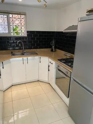 a kitchen with white cabinets and a sink and a refrigerator at Riad Nour Resorts in Marrakech