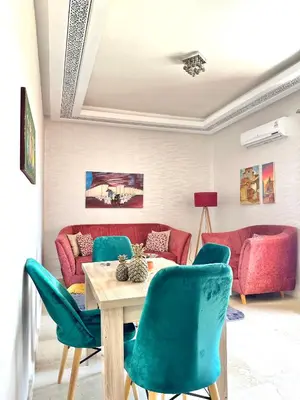 a living room with a table and green chairs at Appartement Denda in Marrakech